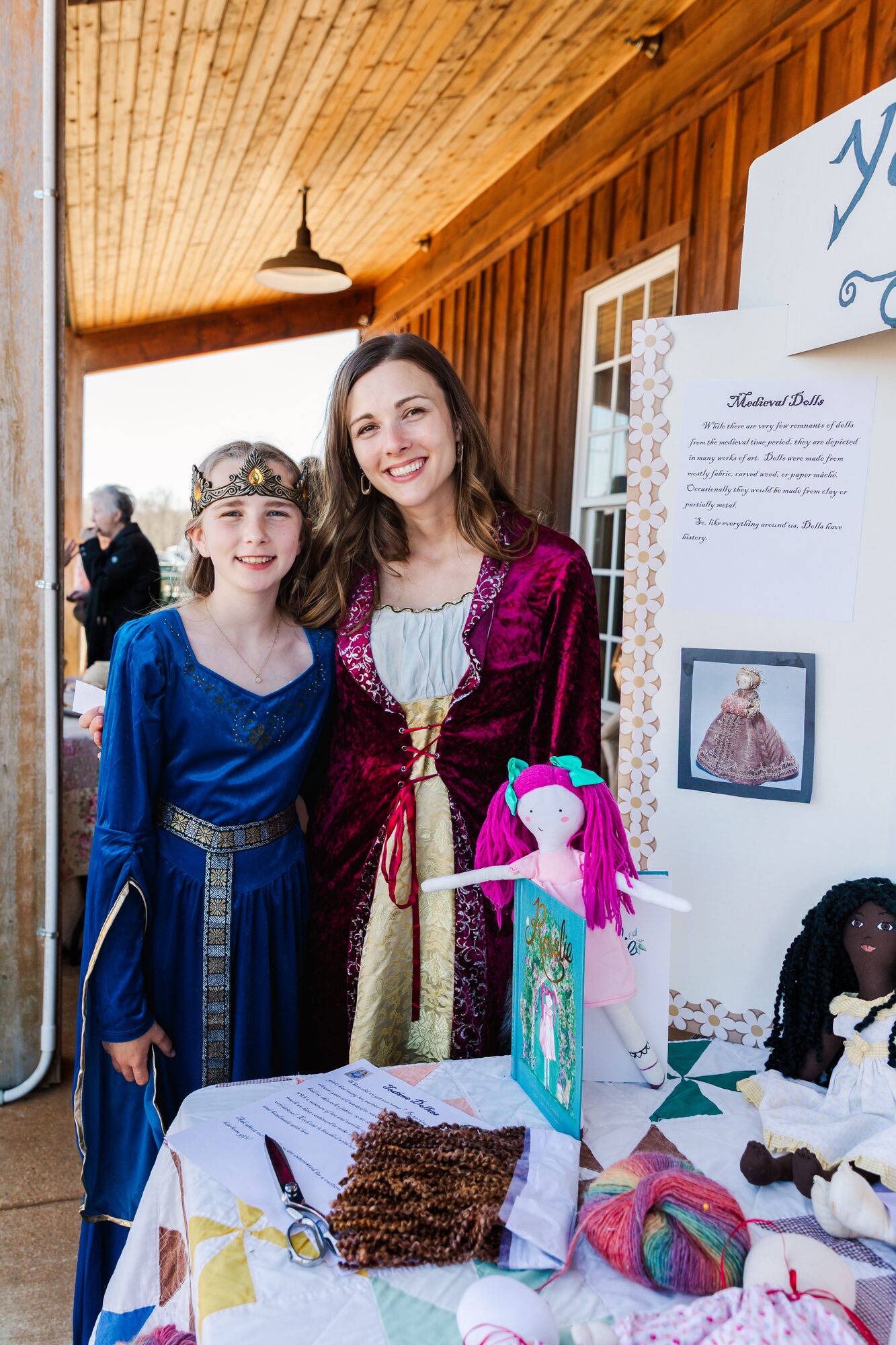 A tutor and student in medieval dress beside a Medieval Dolls history display