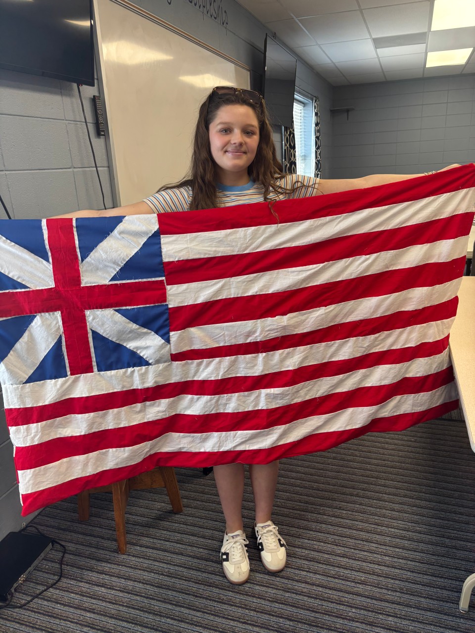 A student holding a replica Grand Union flag from the American Revolution